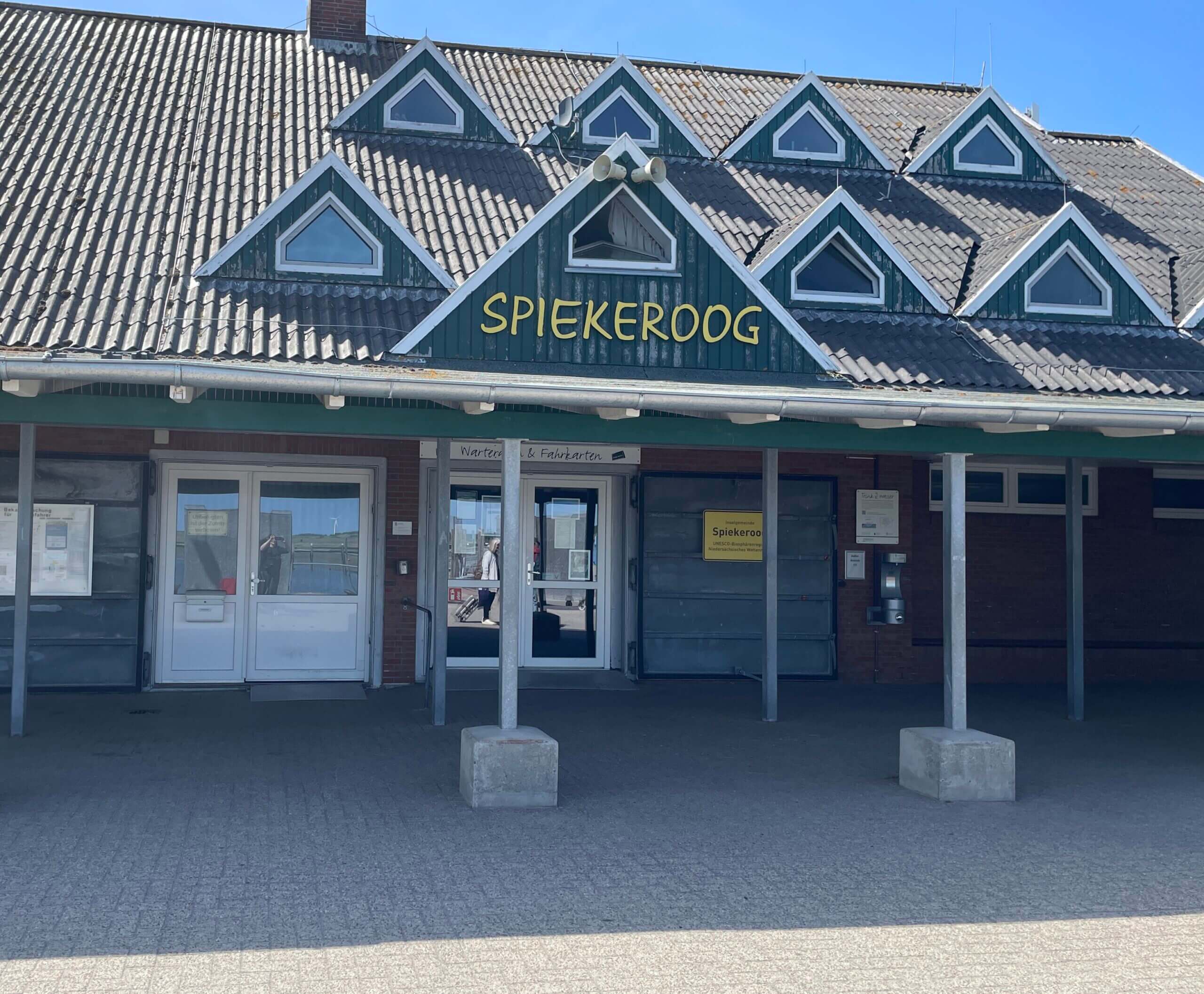 Fähranleger Spiekeroog mit grünem Dach und gelber Schrift – Ankunftspunkt für Inselbesucher.