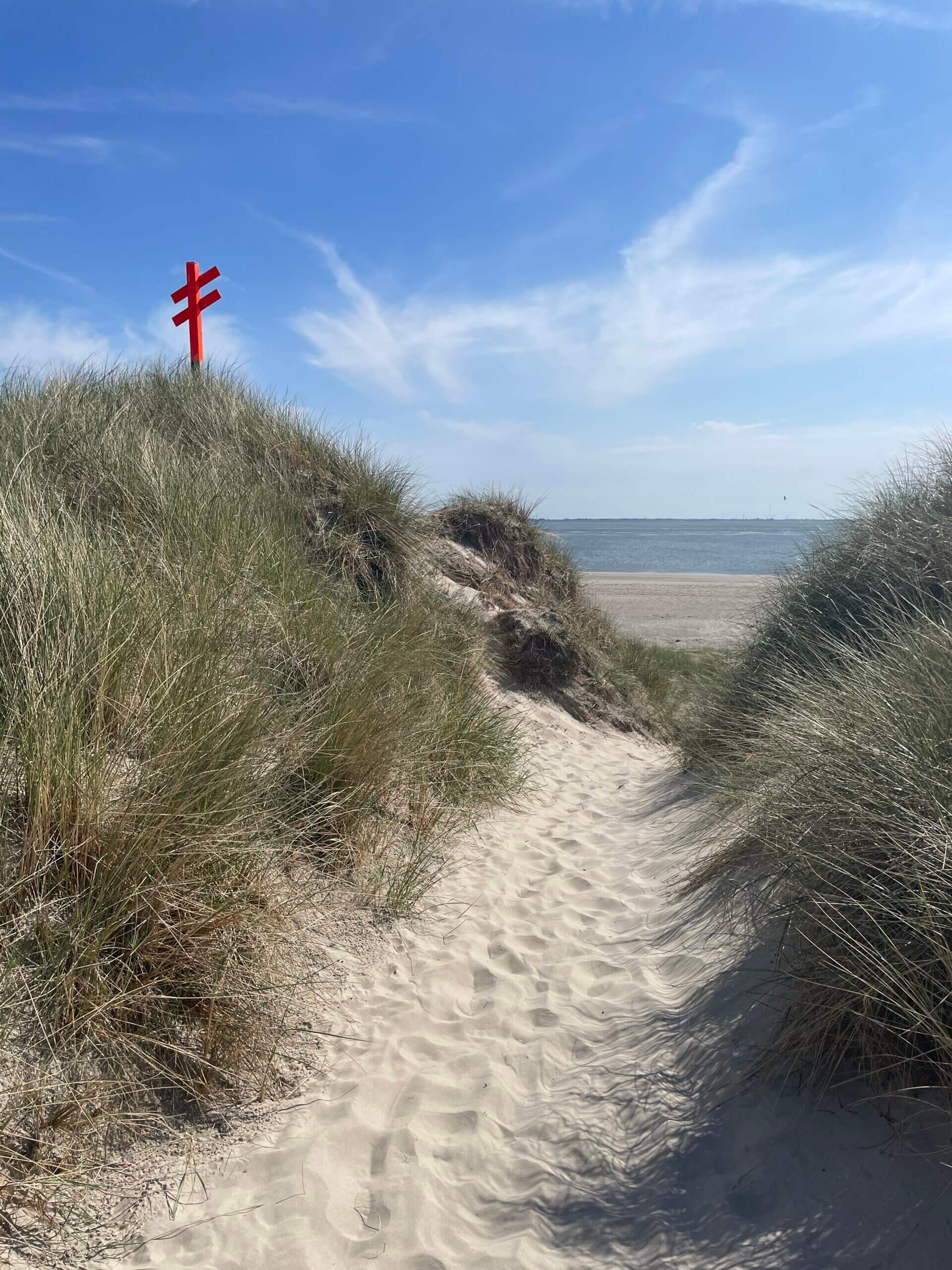 Sandweg durch die Dünen von Spiekeroog mit rotem Kreuz und Blick auf die Nordsee