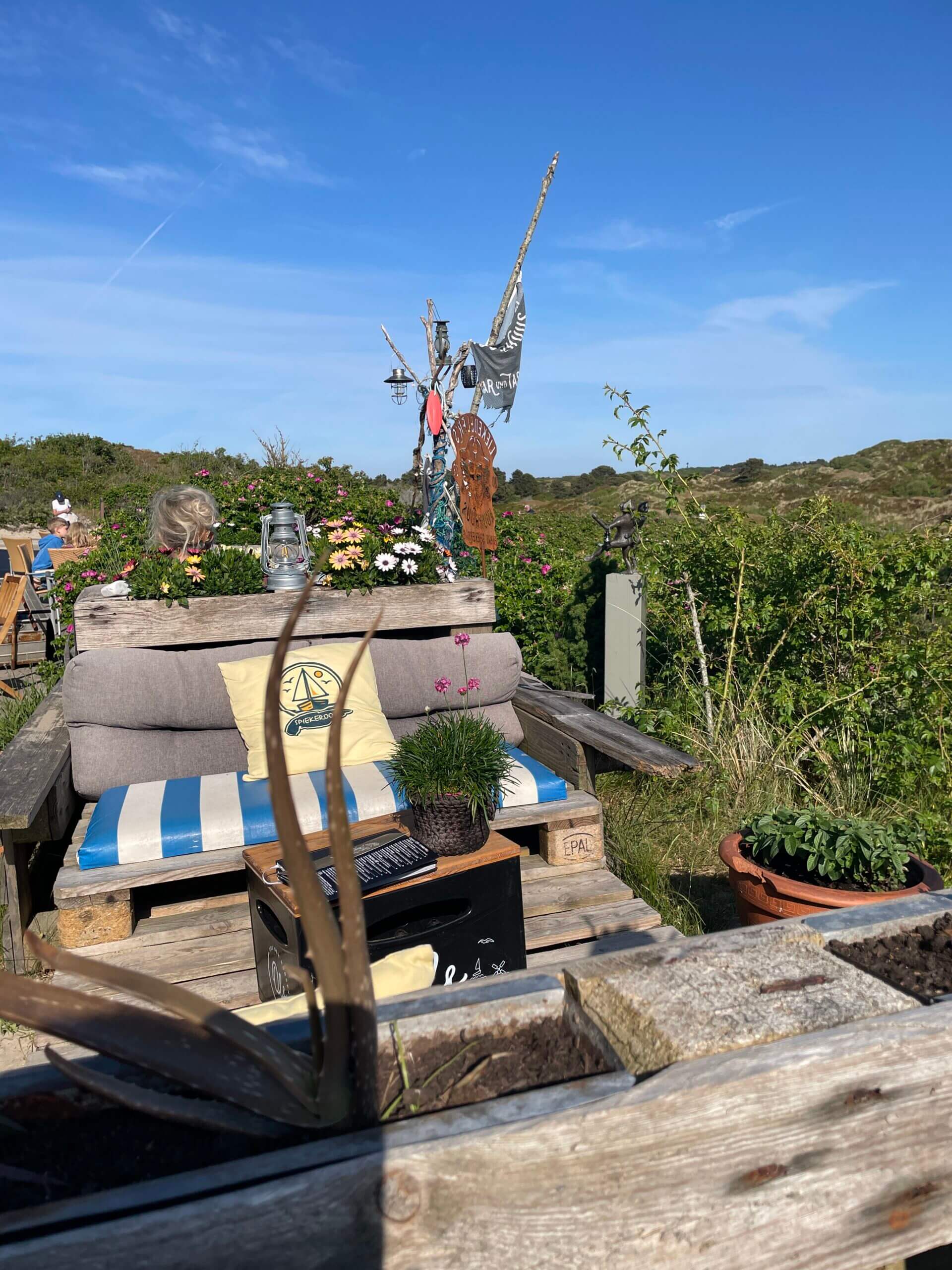 Gemütliche Außenterrasse des Liekedeeler's Kuurhuus auf Spiekeroog mit Palettensofa und Blick in die Dünen