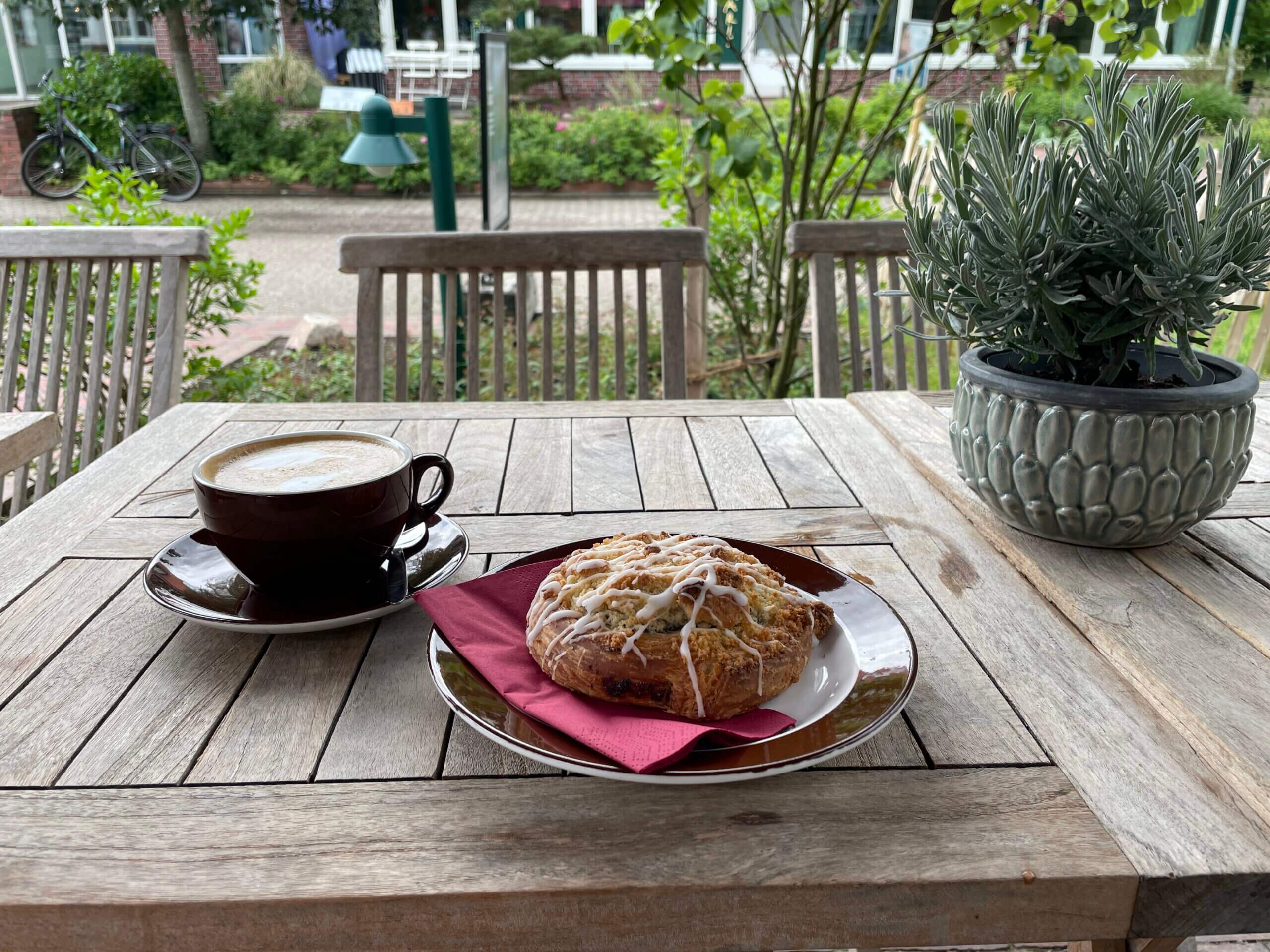 Cappuccino und Mohnschnecke auf einem Terrassentisch im Freien