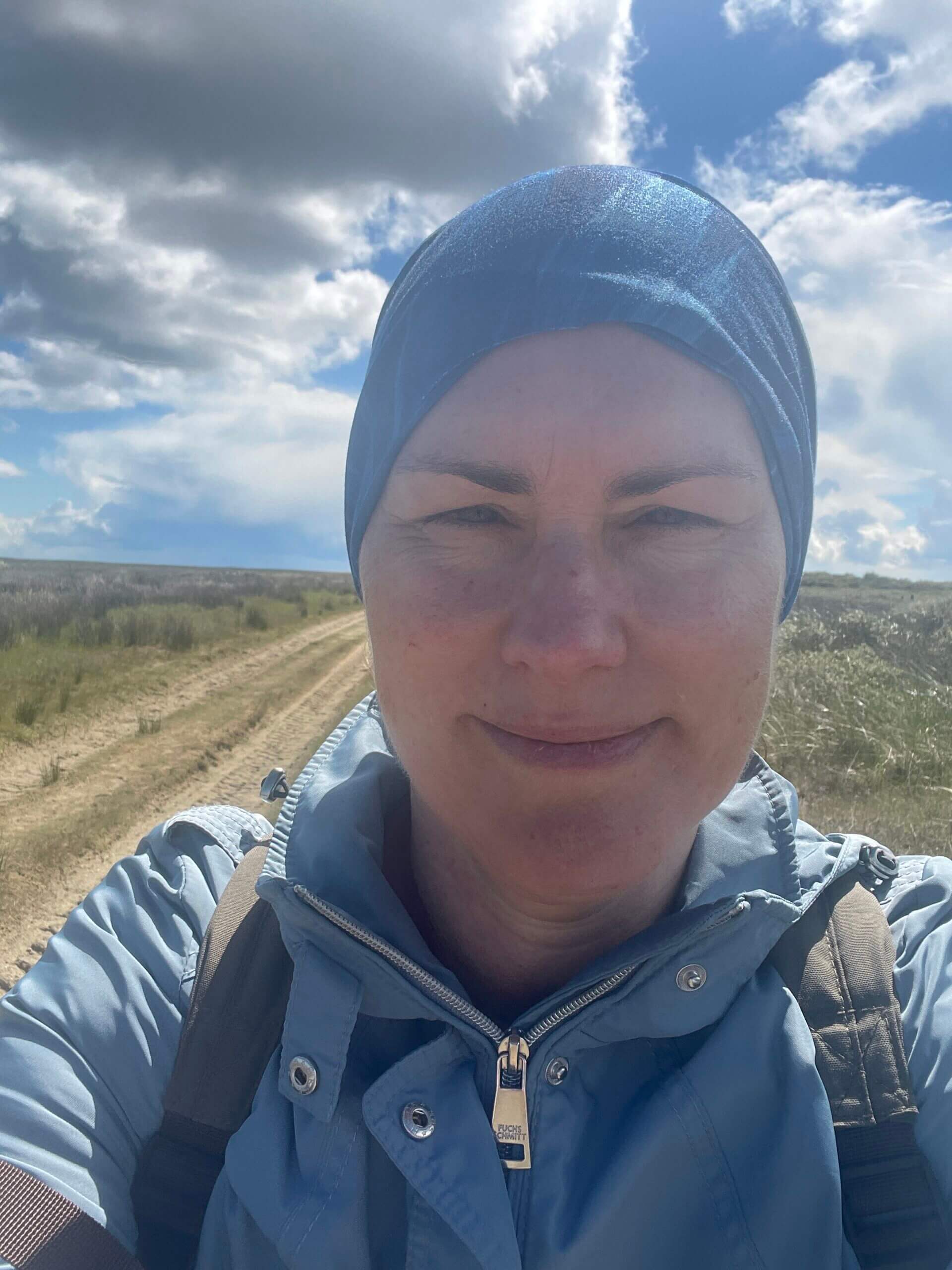 Frau mit blauer Mütze und blauer Jacke im Freien