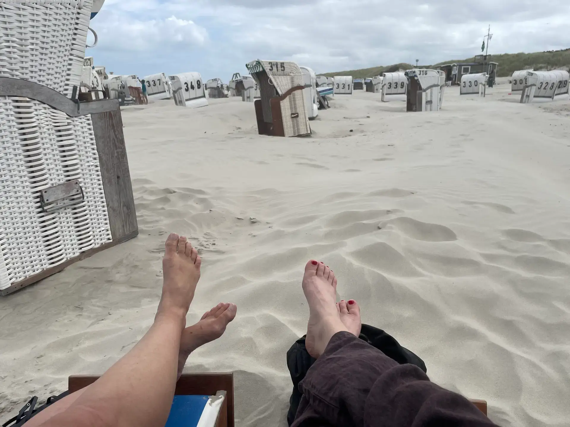 Nackte Füße hochgelegt im Strandkorb mit Blick auf Sanddüne