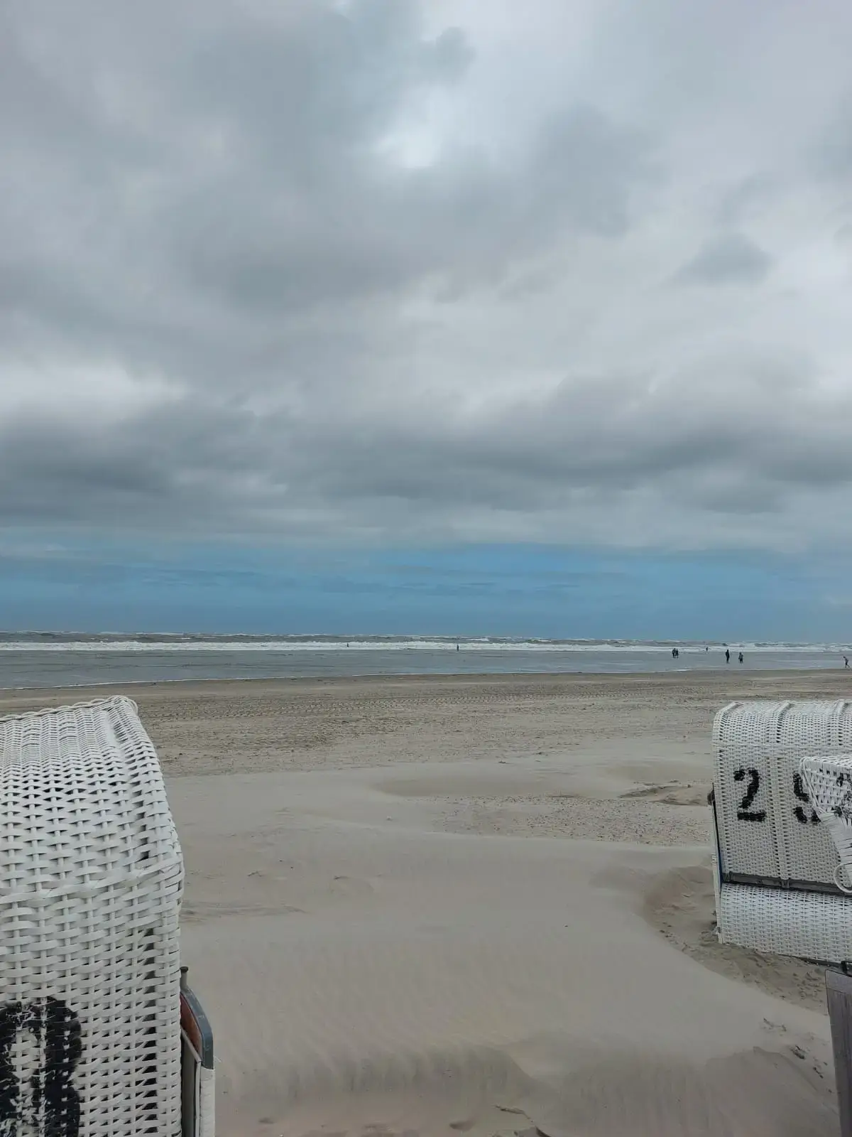 Weiter Sandstrand mit ruhiger See und bewölktem Himmel